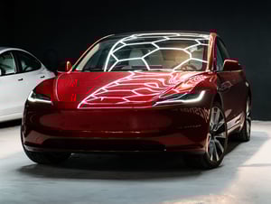 Rotes Tesla Model 3 Hochlandfront andere Seite